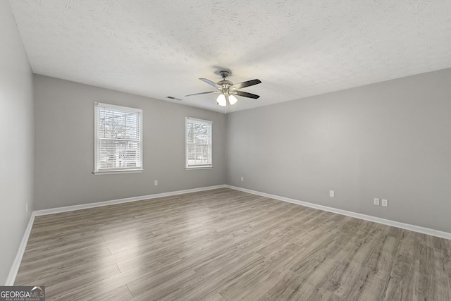 spare room with hardwood / wood-style floors, ceiling fan, and a textured ceiling