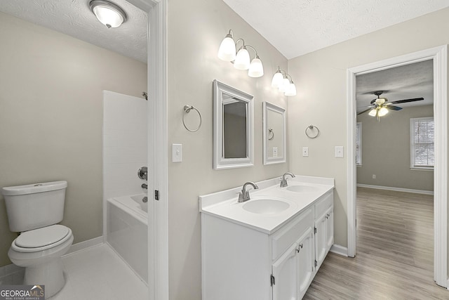 full bathroom featuring vanity, a textured ceiling, bathing tub / shower combination, ceiling fan, and toilet