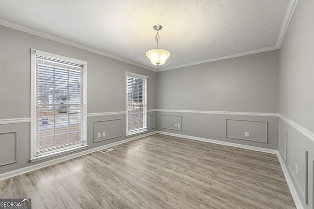 empty room with hardwood / wood-style floors, ornamental molding, and a textured ceiling