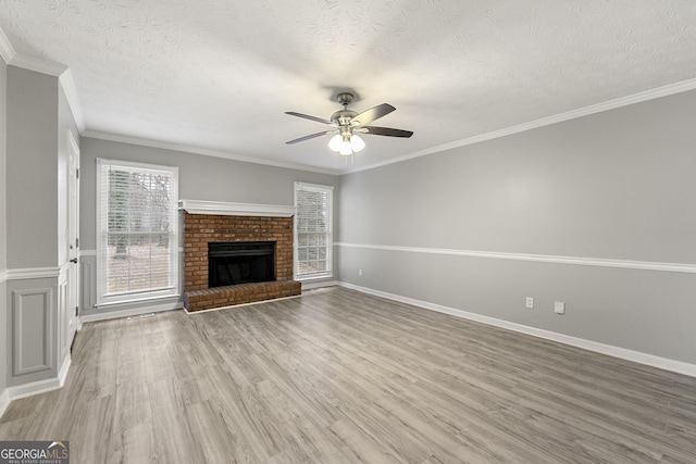 unfurnished living room featuring crown molding, a fireplace, ceiling fan, and wood-type flooring