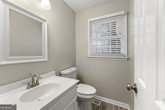 bathroom with vanity, toilet, wood-type flooring, and a textured ceiling