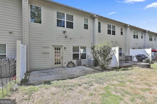 rear view of house with a lawn, central AC, and a patio