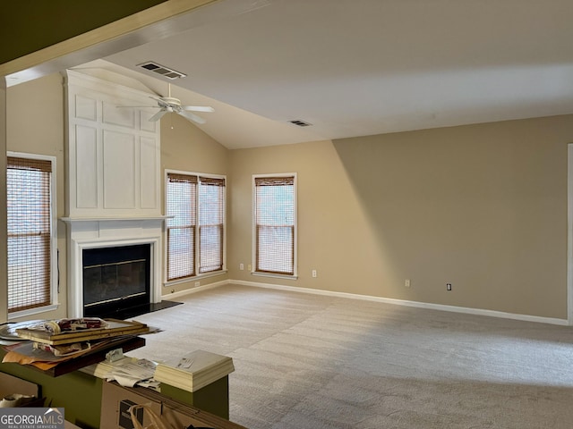 unfurnished living room featuring ceiling fan, light colored carpet, a fireplace, and vaulted ceiling