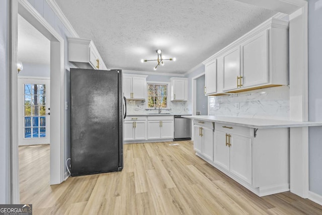 kitchen with black fridge, white cabinets, a healthy amount of sunlight, and stainless steel dishwasher