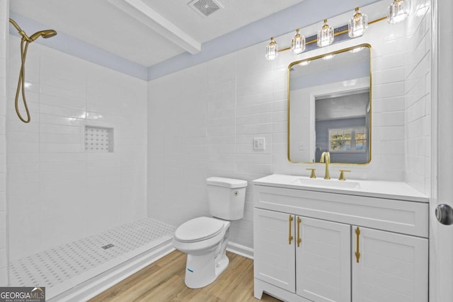 bathroom featuring hardwood / wood-style floors, vanity, toilet, tiled shower, and tile walls