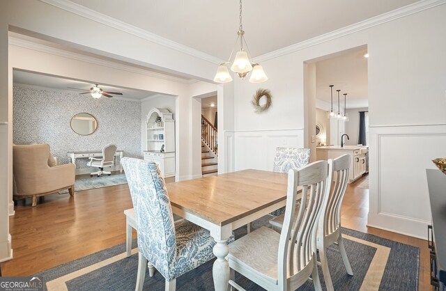 dining space featuring sink, crown molding, and hardwood / wood-style flooring