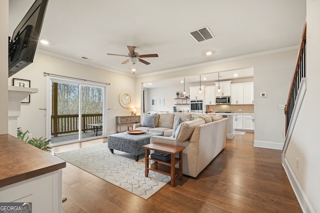 living room with dark hardwood / wood-style flooring, ceiling fan, and ornamental molding