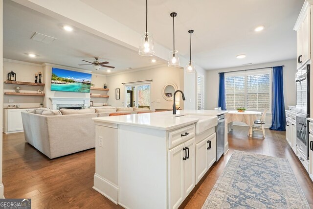 kitchen featuring sink, white cabinets, ceiling fan, an island with sink, and pendant lighting