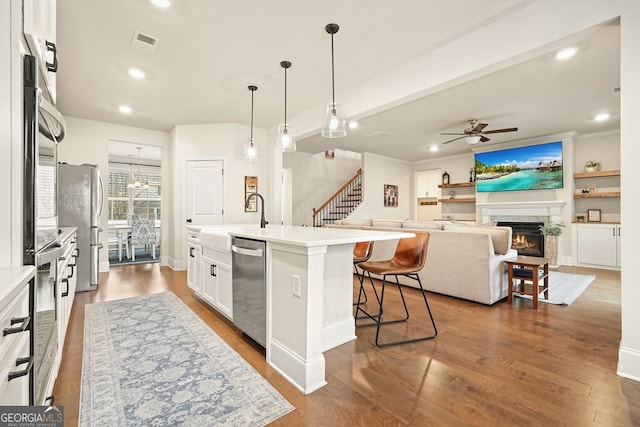 kitchen featuring white cabinetry, ceiling fan, pendant lighting, a kitchen island with sink, and appliances with stainless steel finishes