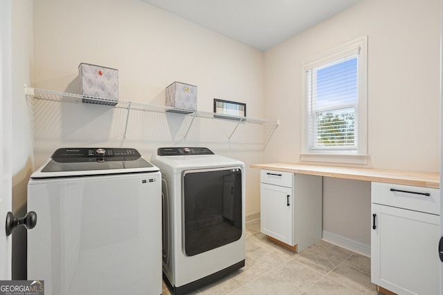 clothes washing area featuring separate washer and dryer and cabinets