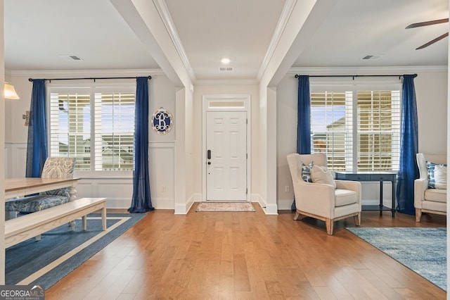 entrance foyer featuring ornamental molding, ceiling fan, and light hardwood / wood-style floors