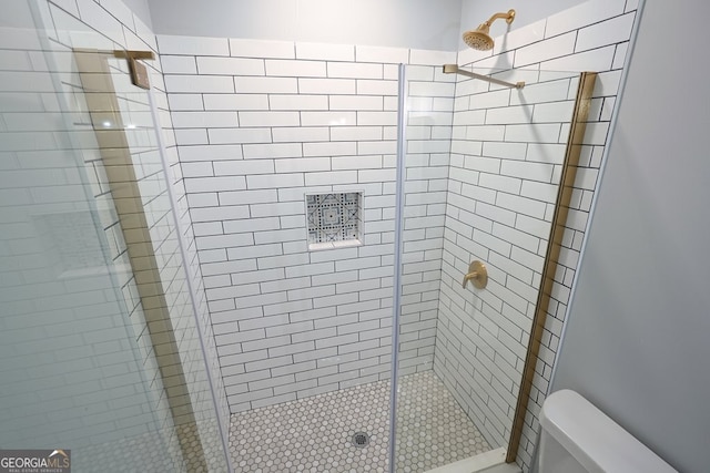 bathroom featuring a shower with shower door and toilet