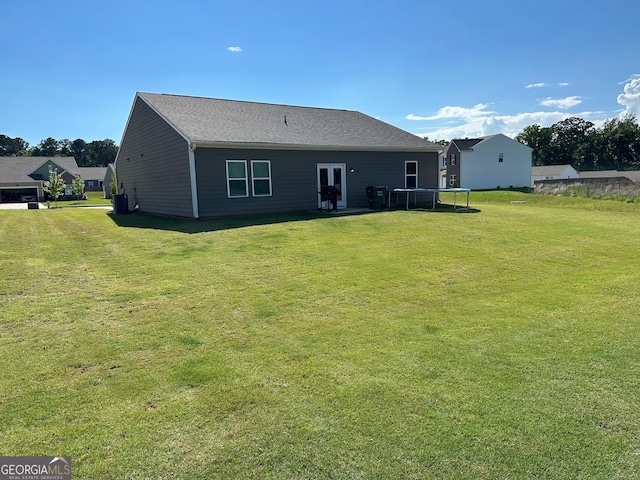 back of house with a lawn and a trampoline