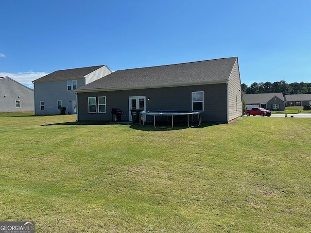 back of house with a trampoline and a lawn