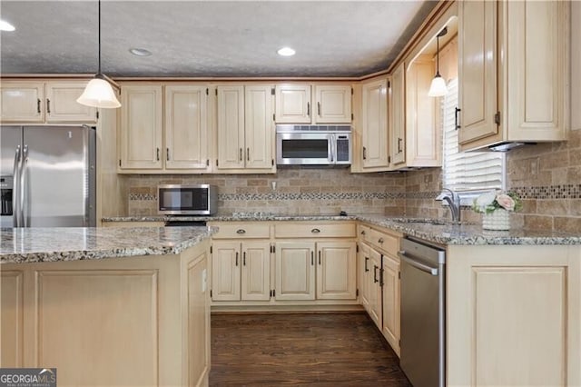 kitchen featuring dark wood-type flooring, sink, hanging light fixtures, stainless steel appliances, and light stone countertops