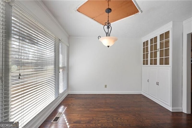 unfurnished dining area with dark hardwood / wood-style flooring, crown molding, and a wealth of natural light