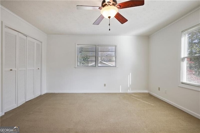 unfurnished bedroom featuring multiple windows, light colored carpet, and ceiling fan