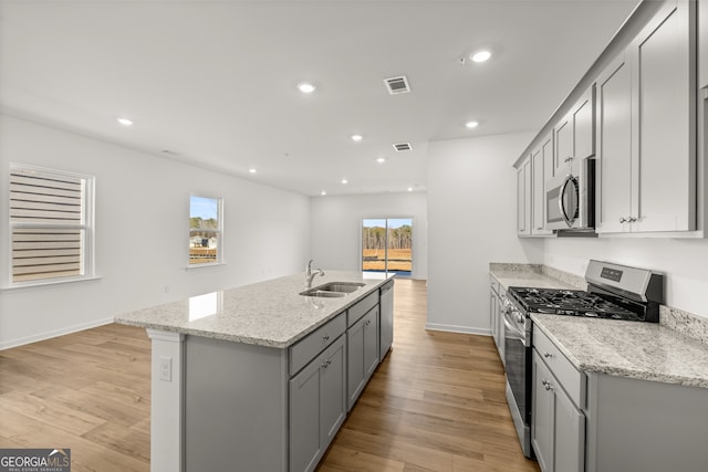 kitchen with gray cabinetry, light stone counters, sink, and appliances with stainless steel finishes