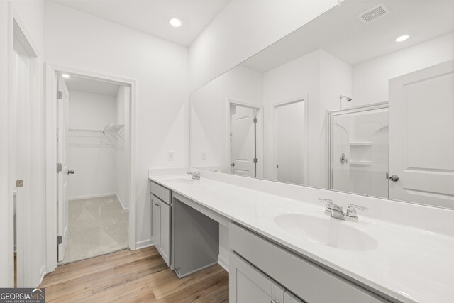 bathroom with hardwood / wood-style floors, vanity, and a shower with door