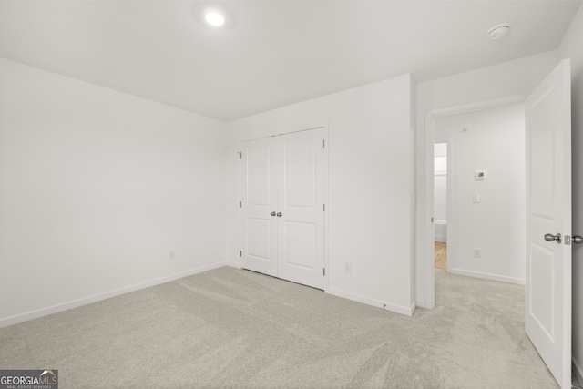 unfurnished bedroom with light colored carpet and a closet