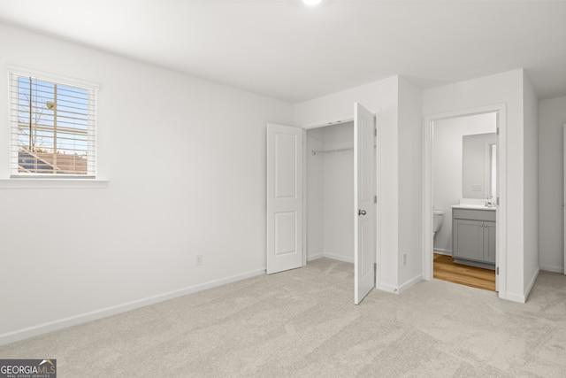 unfurnished bedroom featuring ensuite bathroom, sink, and light colored carpet