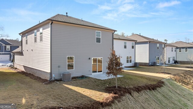 rear view of house with central air condition unit, a patio area, and a lawn