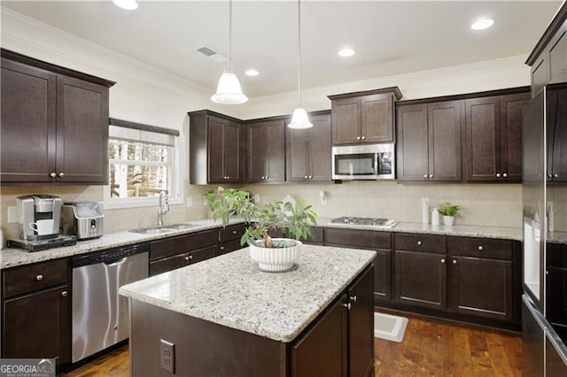 kitchen featuring sink, a center island, hanging light fixtures, stainless steel appliances, and crown molding