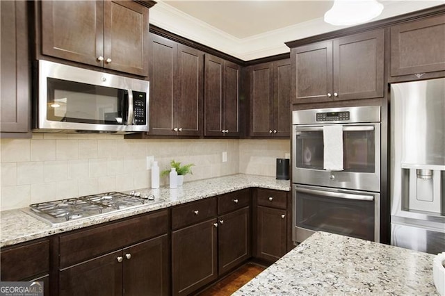 kitchen featuring crown molding, light stone countertops, tasteful backsplash, dark brown cabinets, and stainless steel appliances