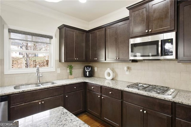 kitchen featuring sink, ornamental molding, stainless steel appliances, and dark brown cabinetry