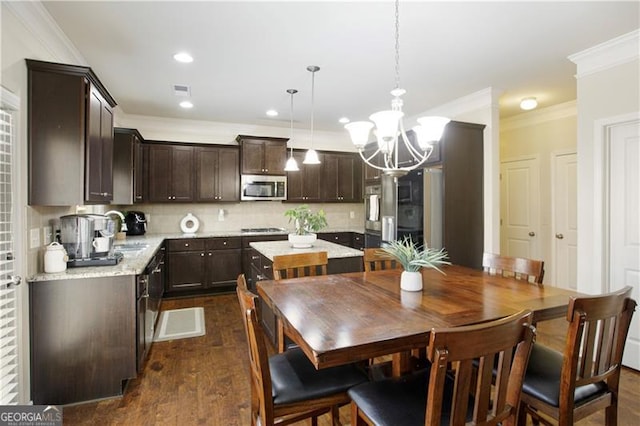 kitchen with dark hardwood / wood-style flooring, tasteful backsplash, ornamental molding, sink, and decorative light fixtures