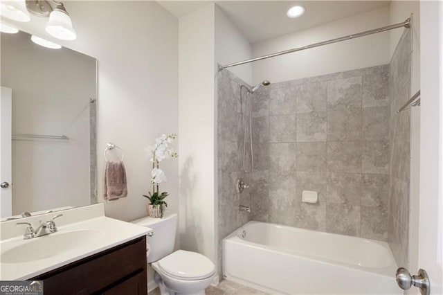 full bathroom with vanity, tiled shower / bath combo, and toilet