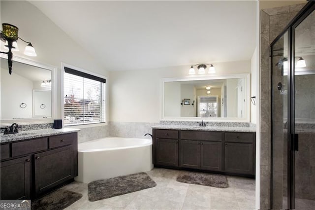 bathroom with tile patterned floors, vanity, shower with separate bathtub, and vaulted ceiling