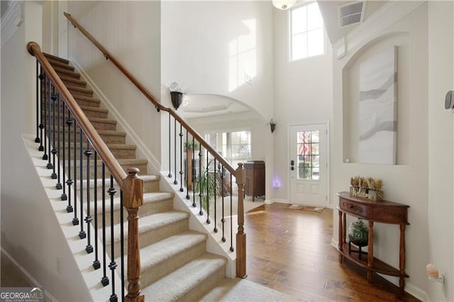 foyer entrance with hardwood / wood-style floors and a towering ceiling