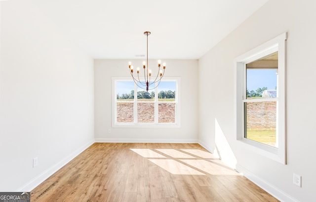 unfurnished dining area featuring a notable chandelier and light wood-type flooring