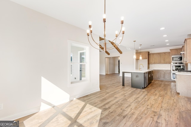 kitchen featuring pendant lighting, an island with sink, appliances with stainless steel finishes, a notable chandelier, and light hardwood / wood-style floors