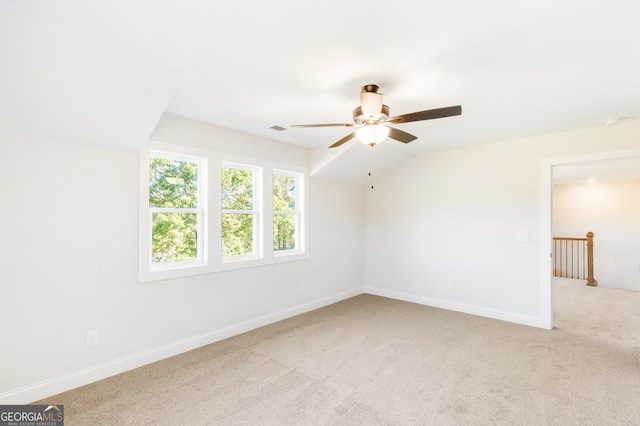 empty room with ceiling fan, light colored carpet, and vaulted ceiling