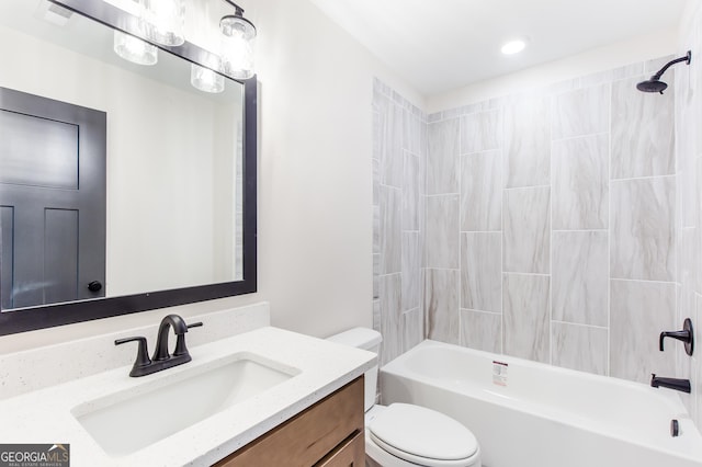 full bathroom featuring tiled shower / bath, vanity, and toilet