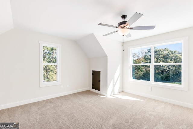 bonus room with light colored carpet, a wealth of natural light, lofted ceiling, and ceiling fan