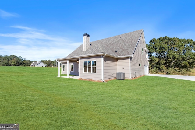 back of property with a garage, a yard, and central AC