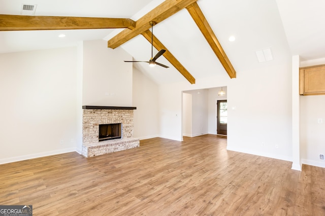 unfurnished living room featuring beam ceiling, ceiling fan, light hardwood / wood-style floors, and a brick fireplace