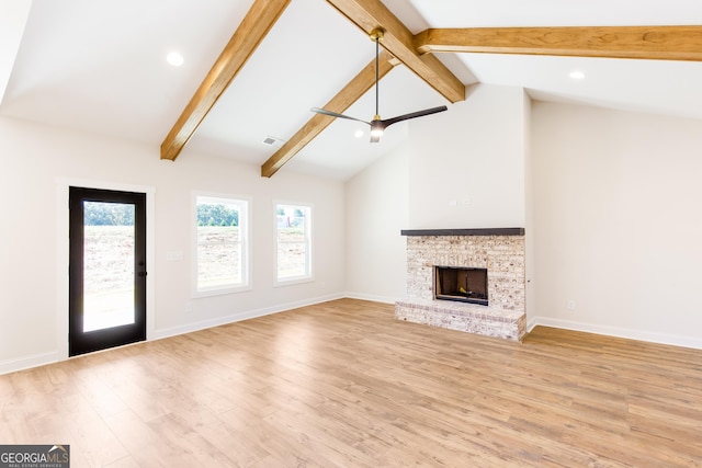 unfurnished living room with a fireplace, ceiling fan, light hardwood / wood-style flooring, and lofted ceiling with beams