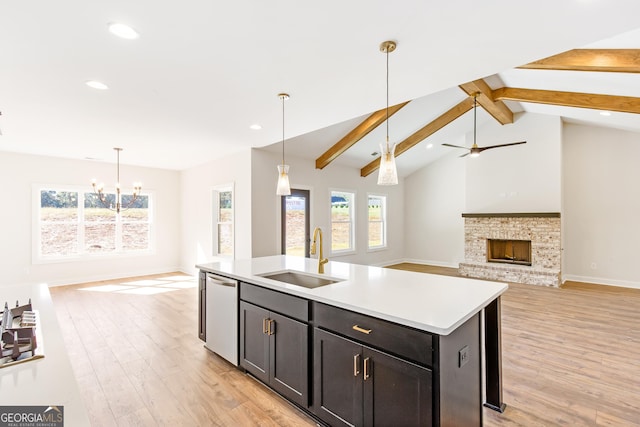 kitchen featuring stainless steel dishwasher, ceiling fan with notable chandelier, sink, a center island with sink, and vaulted ceiling with beams