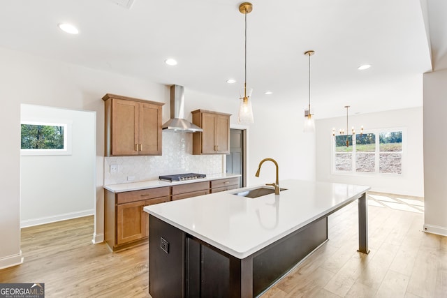 kitchen with a healthy amount of sunlight, pendant lighting, stainless steel gas stovetop, and wall chimney exhaust hood