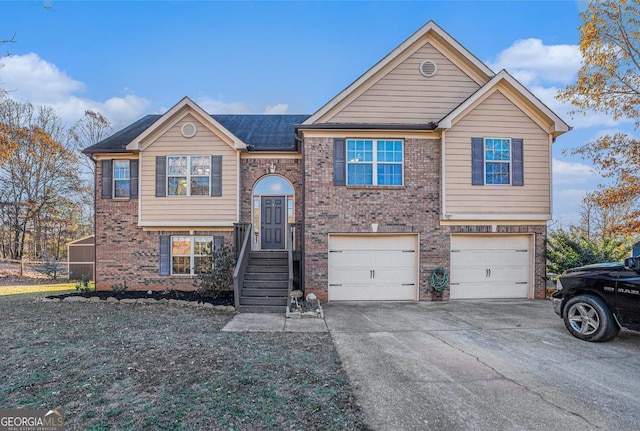 raised ranch featuring concrete driveway, brick siding, and an attached garage