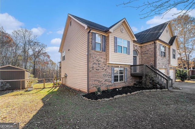 view of side of property featuring a garage, driveway, brick siding, and fence