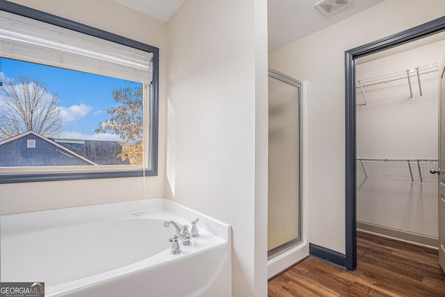 bathroom with wood-type flooring and shower with separate bathtub