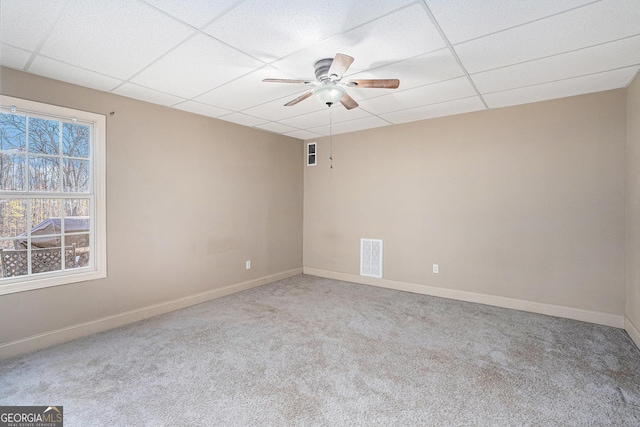 empty room featuring a paneled ceiling, ceiling fan, and light carpet