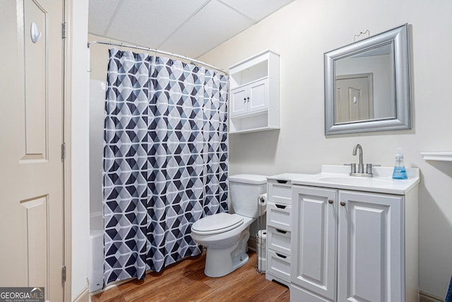 full bathroom featuring a drop ceiling, shower / bath combination with curtain, wood-type flooring, toilet, and vanity