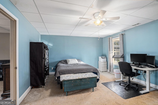 bedroom featuring ceiling fan, a drop ceiling, and light colored carpet