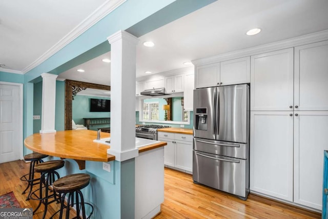 kitchen featuring ornamental molding, stainless steel appliances, light hardwood / wood-style flooring, white cabinets, and a breakfast bar area